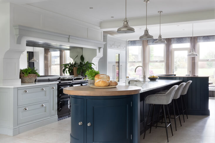 Renovation of periodic georgian kitchen with a large island, a mirrored splashback and silver light fixtures with shaker cabinets