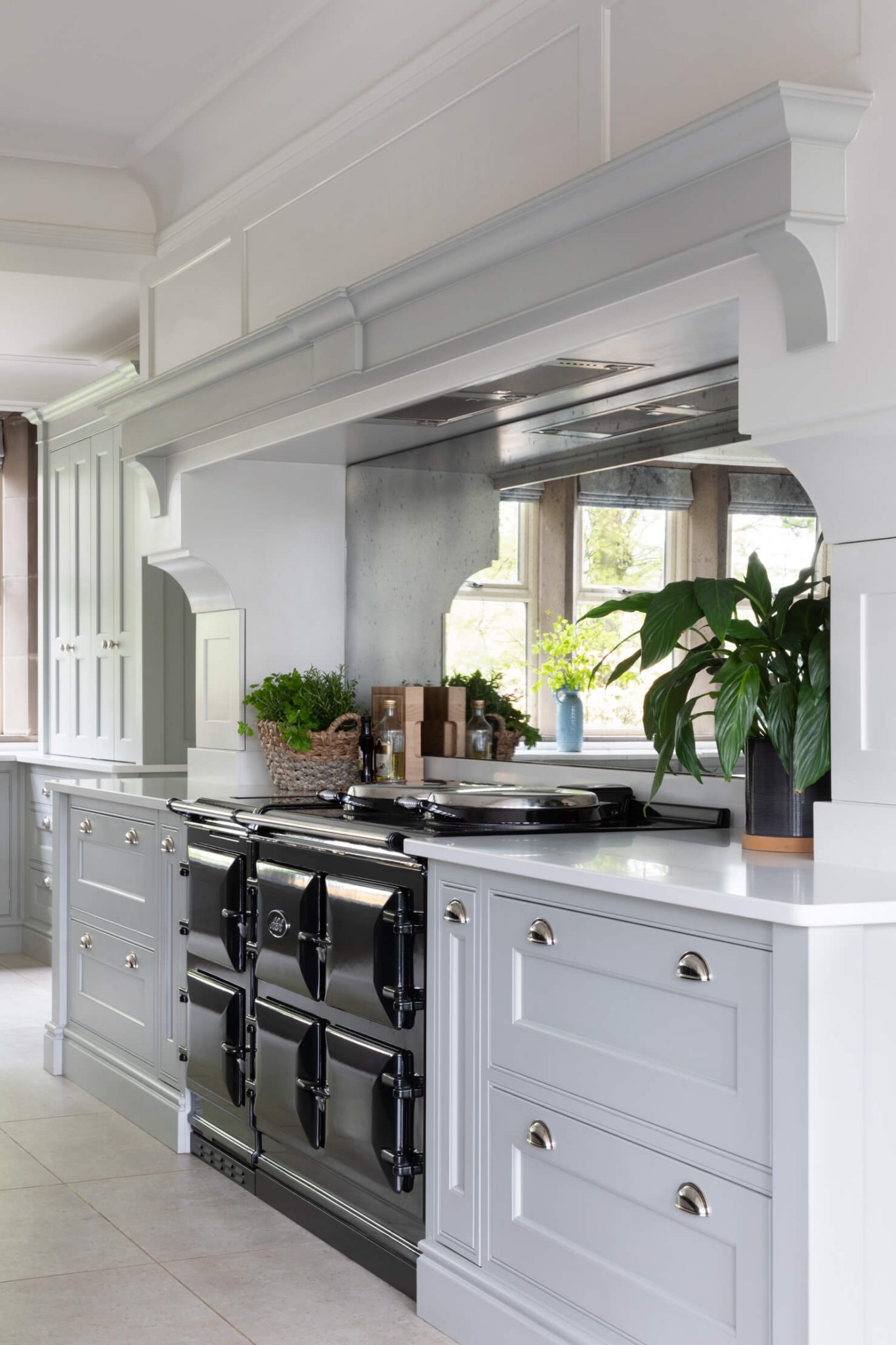 A high-range stove cooker in a Georgian kitchen, surrounded by a chimney and bespoke cabinetry, with a mirrored splashback.